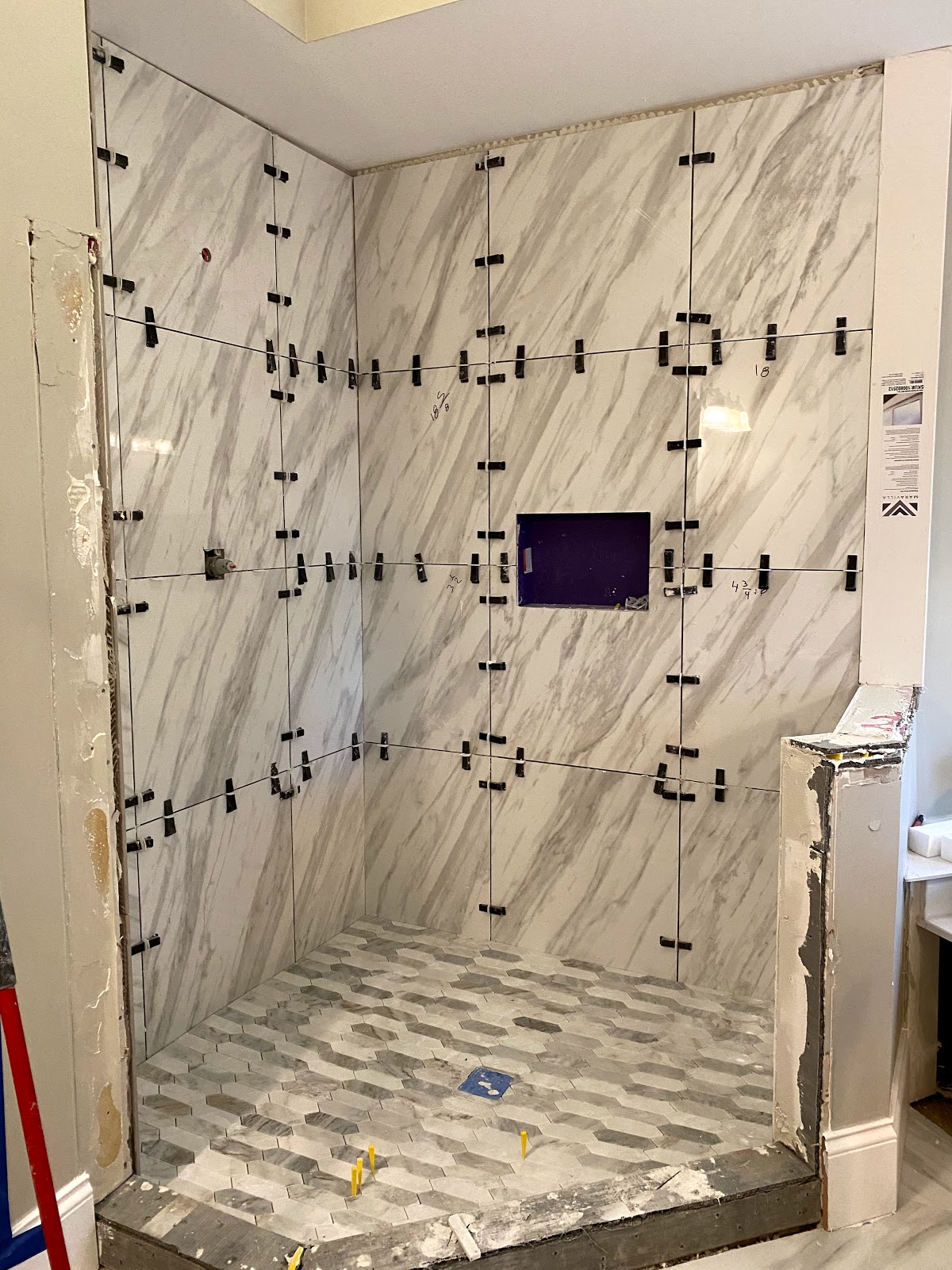 TGP Home Services — marble tile shower wall install in progress with leveling clips and hexagon mosaic floor