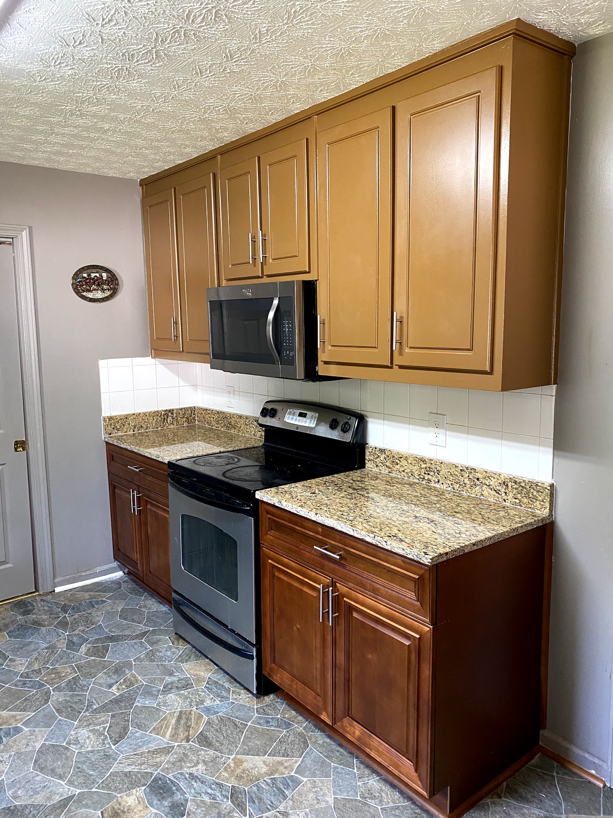 TGP Home Services — kitchen with refinished stained wood cabinets, granite counters, stainless range, and slate-tile floor