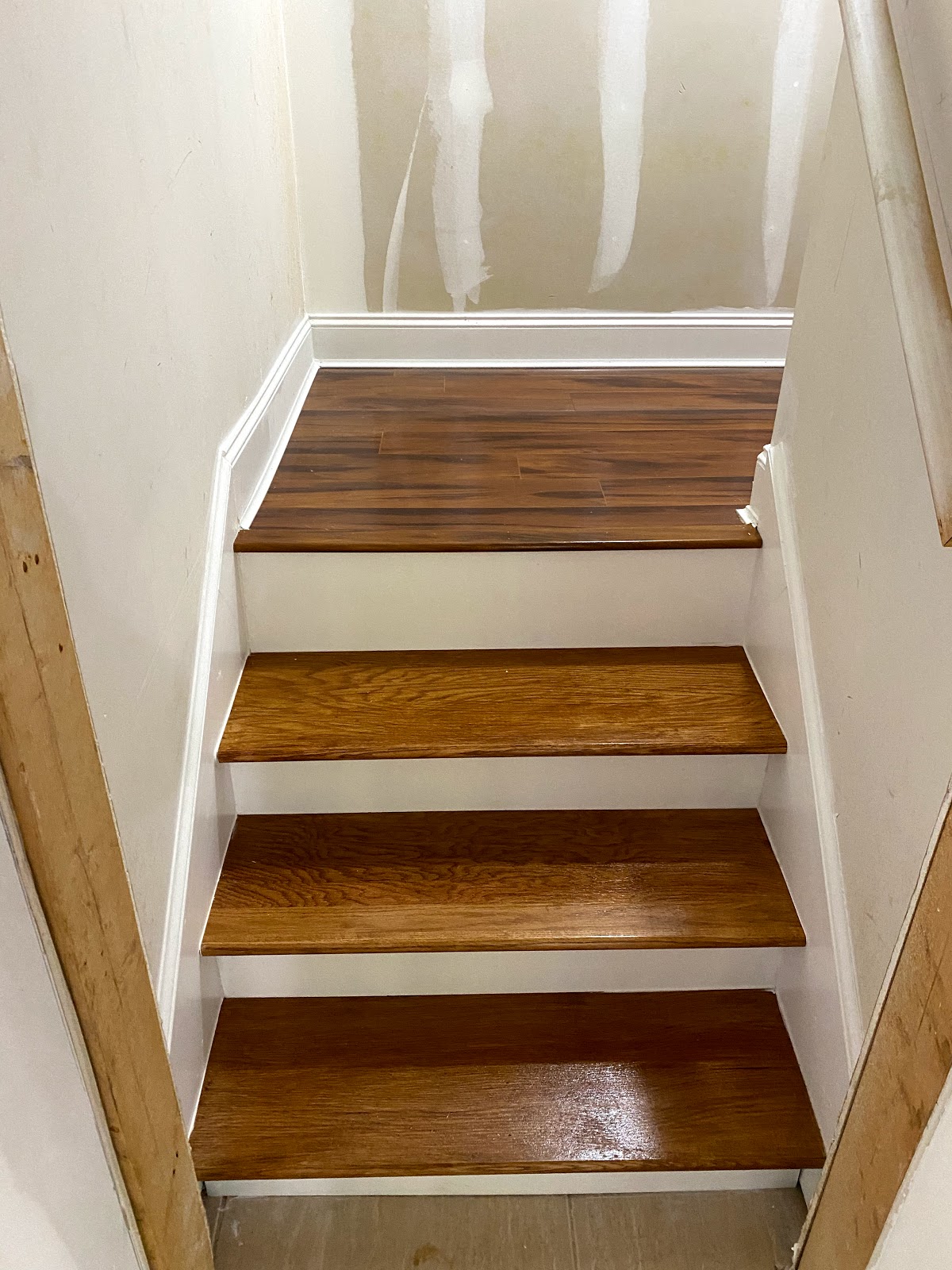 TGP Home Services — freshly stained solid wood stair treads mid-install in an unfinished stairwell